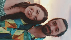 VERTICAL VIDEO: Young couple standing on the beach at sunrise