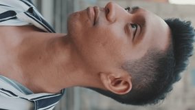 VERTICAL VIDEO:Close-up of smiling young man tourist turning his head and looking at the camera