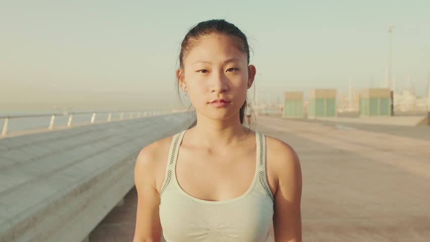 girl in sports top walks forward along the promenade and looks at the camera