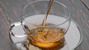 Pouring black tea into cup. Stream fresh aroma hot black tea into transparent cup. Slow motion shot - Powered by Shutterstock - Get 15% off with code: PIKWIZARD15