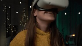 Young woman playing on guitar using VR helmet indoor. Girl playing on guitar with wearable VR. Virtual concert at home.