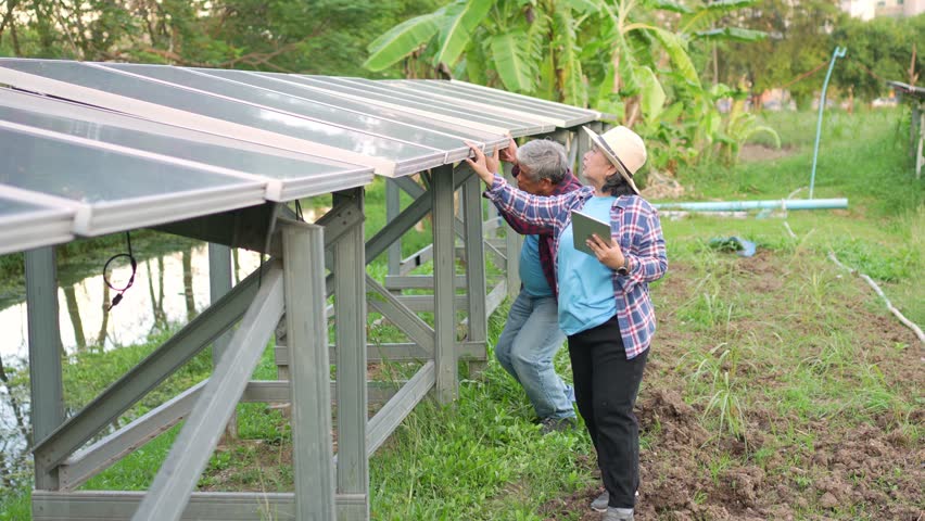 Elderly Asian farmers use smartphones to adjust solar cells degree and check solar cell performance after rain and Dust and dirt stains on the solar cell. Concept of farming technology. Royalty-Free Stock Footage #1102228205