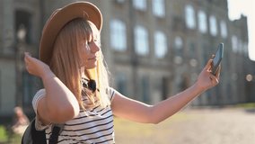 Happy positive female tourist with good mood enjoying making selfie with mobile phone. Caucasian woman tourist in european city making pictures with smartphone. High quality 4k video footage