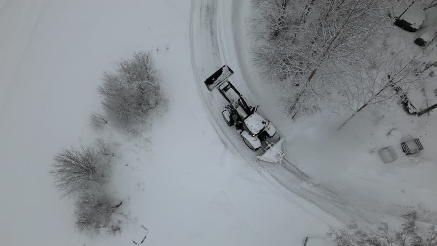 after heavy snowfall a tractor is plowing snow