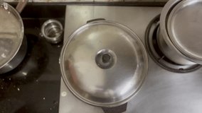 A cinematic footage or video of selective focus of the lid of a hot pan being removed by an Indian woman's hand. The south Indian food Paddu(Paniyaram) was being cooked in the pan.