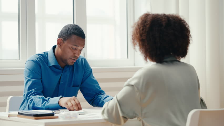 African American man interviewing woman for a job and reading her CV, employment Royalty-Free Stock Footage #1102233667