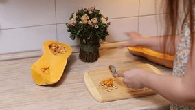 Unrecognizable housewife carving fresh raw butternut squash, removing seeds to wooden cutting board in the kitchen. Halloween holiday meal recipe, healthy food cooking. Vegetable baking. Video 4k