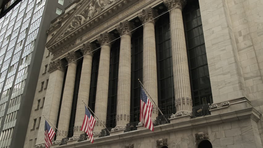 Famous Wall street and the building in New York, New York Stock Exchange with patriot flag. Wall Street road sign in the corner of New York Stock Exchange. New York Stock Exchange 2023