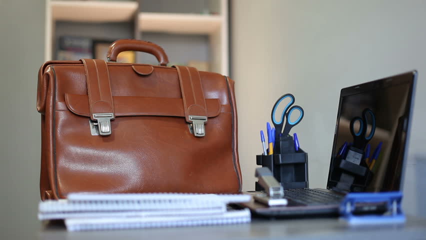 An unknown man takes documents from the table, puts them in a briefcase, and leaves work. End of the working day in the company. Royalty-Free Stock Footage #1102236215