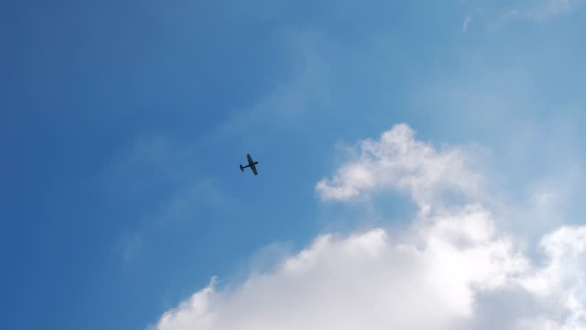 Vintage plane soars in sky. Light engine pleasure plane flies high in blue cloudy sky. Propeller old plane in air. View from the ground, below. Light aircraft flying . Royalty-Free Stock Footage #1102238205