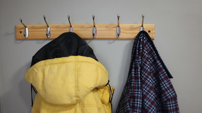 A man takes a blue plaid light jacket from a hanger. The man leaves the house.