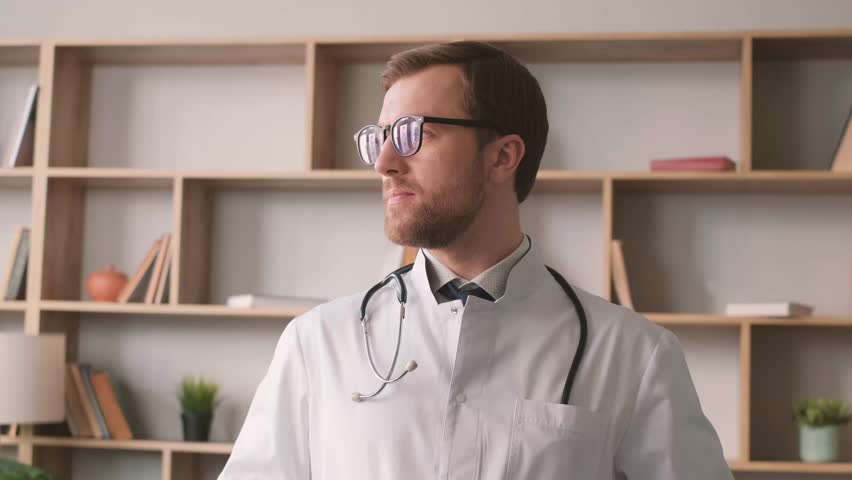 Portrait of a doctor in a white coat and glasses, he is looking at the camera and smiling. Royalty-Free Stock Footage #1102241983