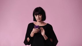 4k video of one woman using her phone over pink background.