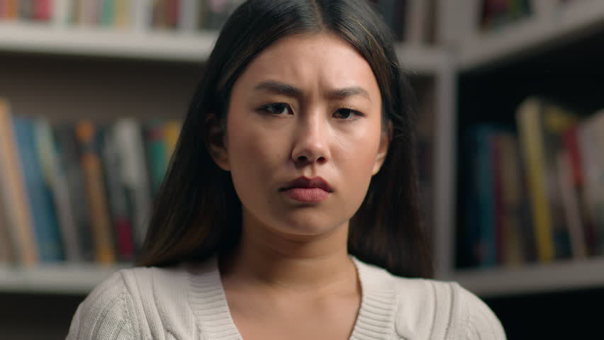 Female portrait upset sad asian woman student looking at camera with distressed frustrated expression in university library desperate girl lady feel sadness for failed result exam received bad news Royalty-Free Stock Footage #1102243395