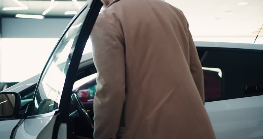 Young male customer is sitting inside new car while shopping in modern showroom Royalty-Free Stock Footage #1102243473
