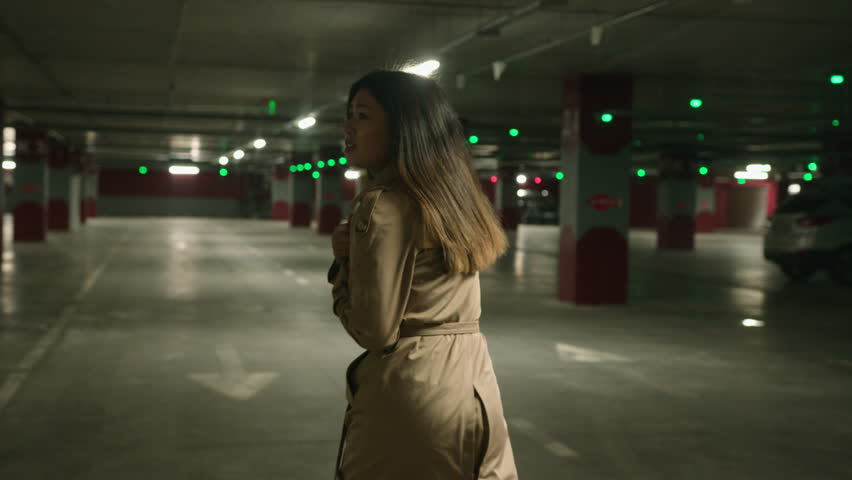 Back view frightened Asian woman scared girl running in parking dark underground subway afraid stressful lady victim feel panic run from pursuit threat dangerous chase alone female walking look behind