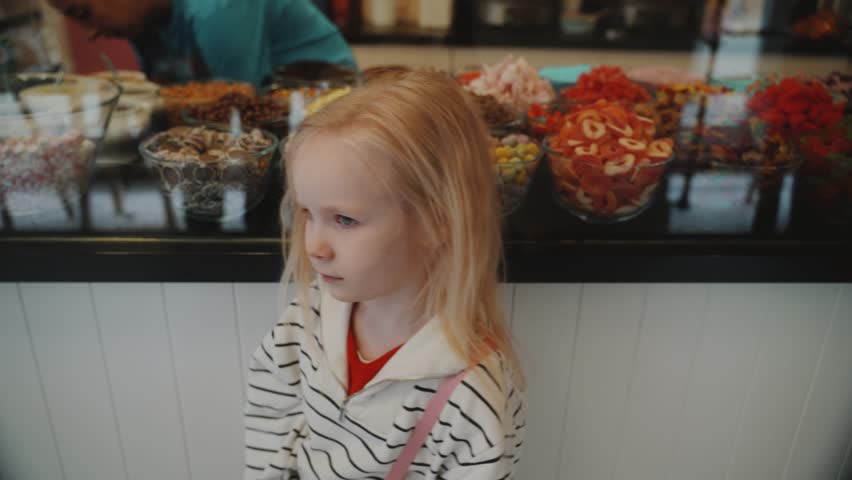 Cute little girl stands in front of an ice cream shop window. Kilkenny