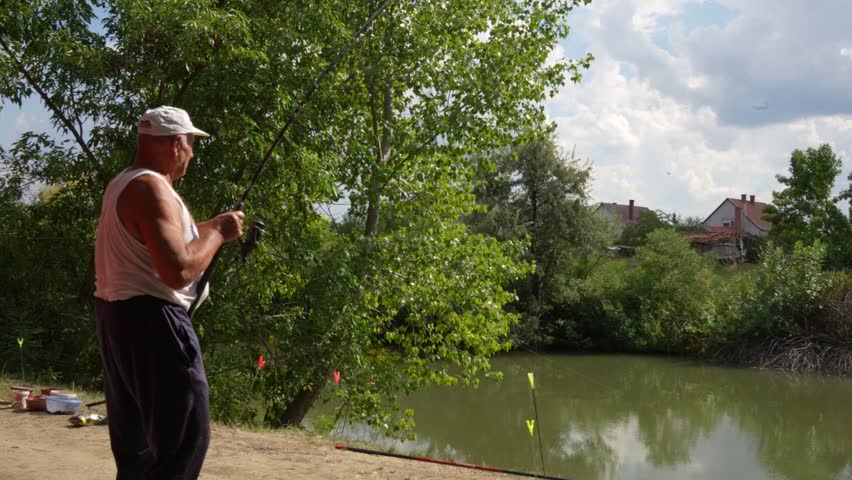 Old angler catching and fighting a fish