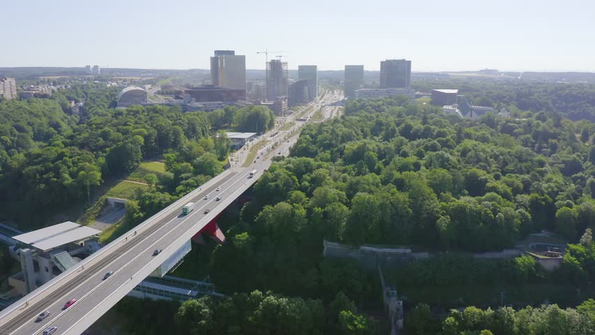 Inscription on video. Luxembourg, Avenue John F. Kennedy, An area with modern skyscrapers. Pont rouge. Different colors letters appears behind small squares, Aerial View