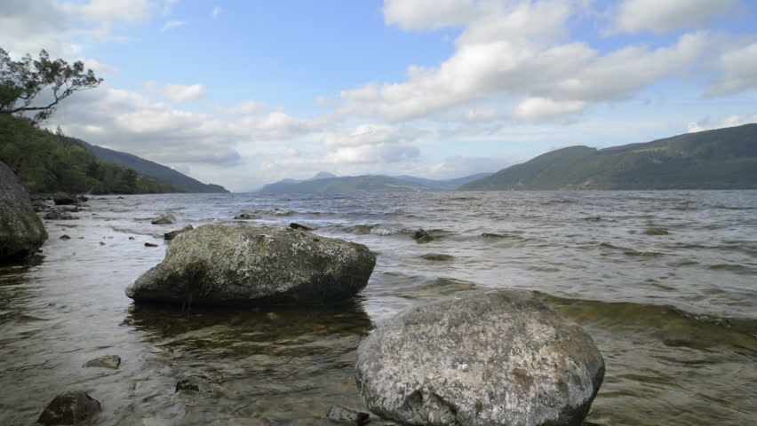 Beautiful Loch Ness landscape, Scotland, on sunny day. Low level view with shore rocks in foreground.