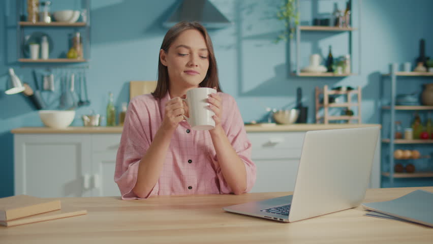 Smiling Business Woman Having Coffee Break at Work from Home. Portrait of Relaxed Young Woman Drinking Cup of Tea While Working on The Laptop. Concept of Freelance and Modern Technology. Royalty-Free Stock Footage #1102257151