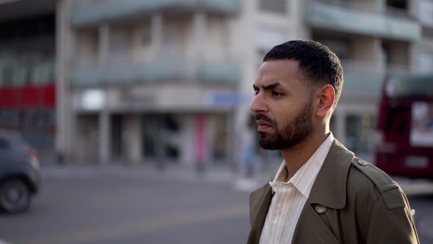 Portrait of a young Middle Eastern man standing on a street and looking up at the sky with a hopeful and faithful expression on his face. He turns his head upwards and smiles Royalty-Free Stock Footage #1102257499