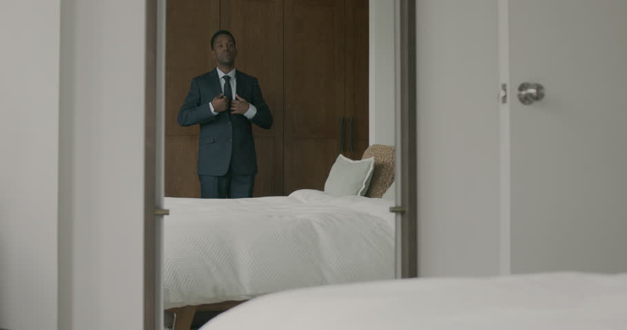 African American Businessman in Suit using a Smartphone in Hotel Bedroom