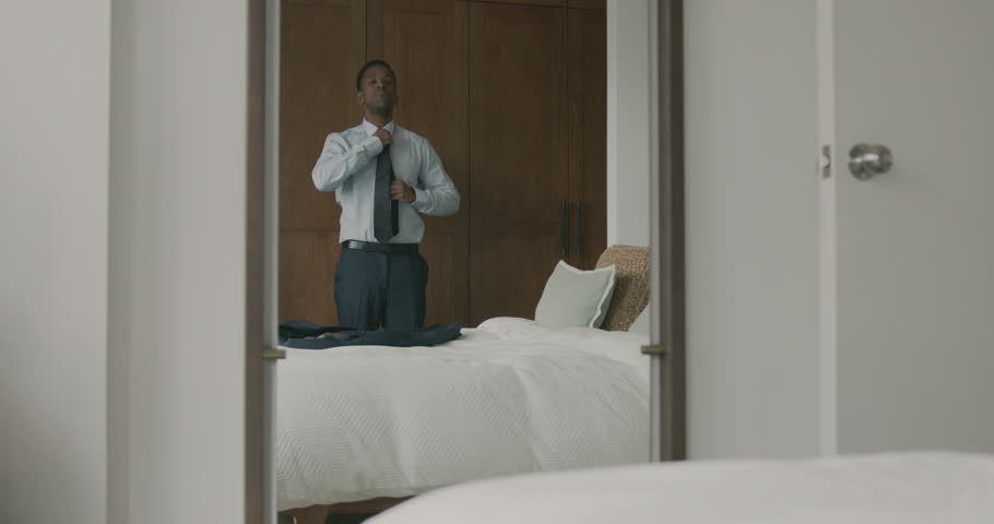 African American Businessman adjusting his tie in Bedroom, getting ready for Work