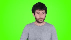 Caucasian young man drinks a full glass of water and feels satisfied, with green screen in the background. Healthy lifestyle concept