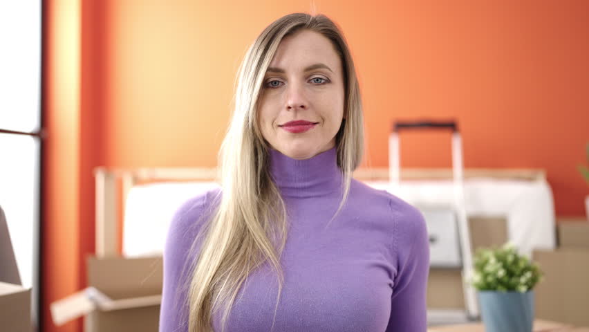 Young blonde woman smiling confident holding key at new home
