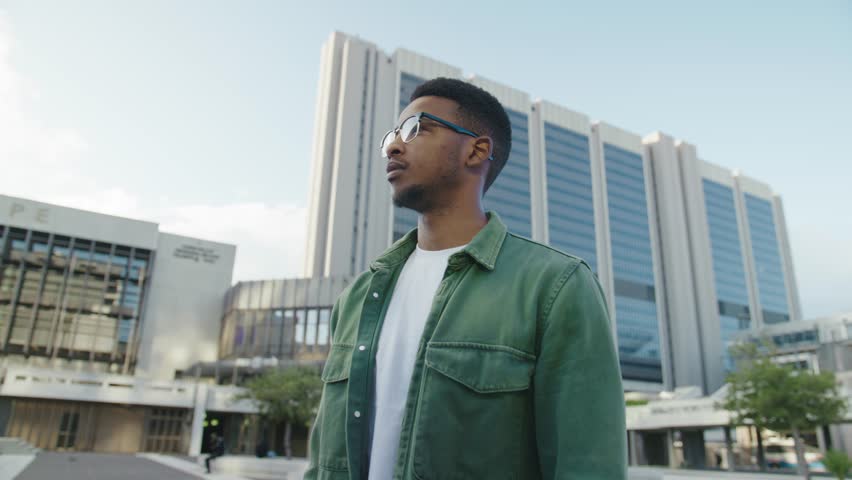 Young black man in casual clothing smiling and looking at camera with arms crossed in street Royalty-Free Stock Footage #1102264111