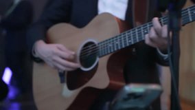 Musician in suit plays acoustic guitar on stage, sings. Concert footage with music concept. Perfect for music magazine and instrument ads.