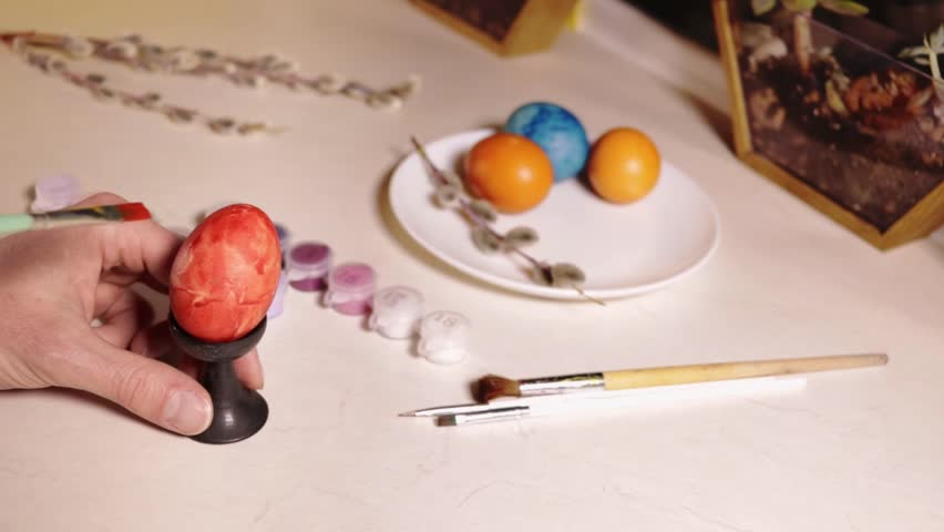 painting an egg red with a brush close-up

