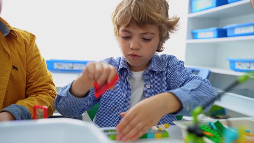 Robotics programming class. Children construct and code Robot. STEM education using constructor blocks and laptop tablet, remote control joystick. Technology educational development for school kids. A