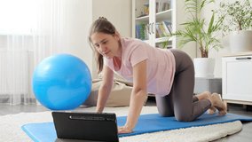 Young smiling woman doing online fitness training session from home. Concept of healthcare, sports and yoga at home