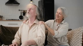 Health, body muscles stiff problem of senior couple, caucasians mature, adult retired husband, wife pain with back pain ache holding massaging rubbing shoulder hurt or sore, painful sitting on sofa. - Powered by Shutterstock - Get 15% off with code: PIKWIZARD15