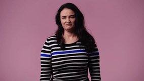 4k video of one woman with negative facial expression showing thumb down over pink background.