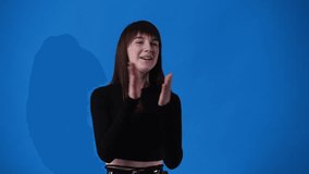 4k slow motion video of one girl claps his hands and smiling over blue background.
