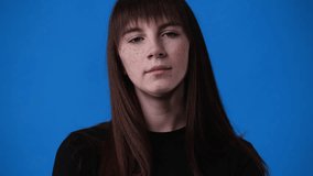 4k video of one girl posing with a negative expression over blue background.