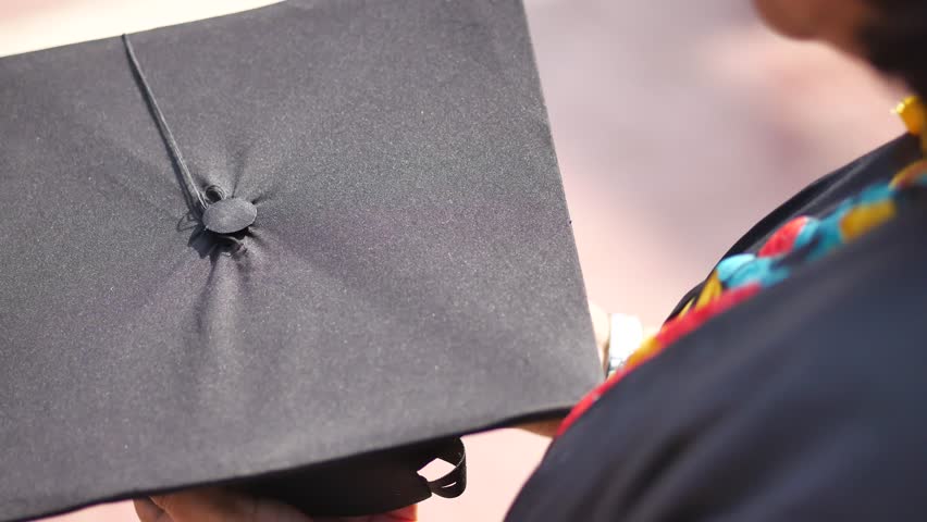 Student hold hats in hand during commencement success on yellow background 