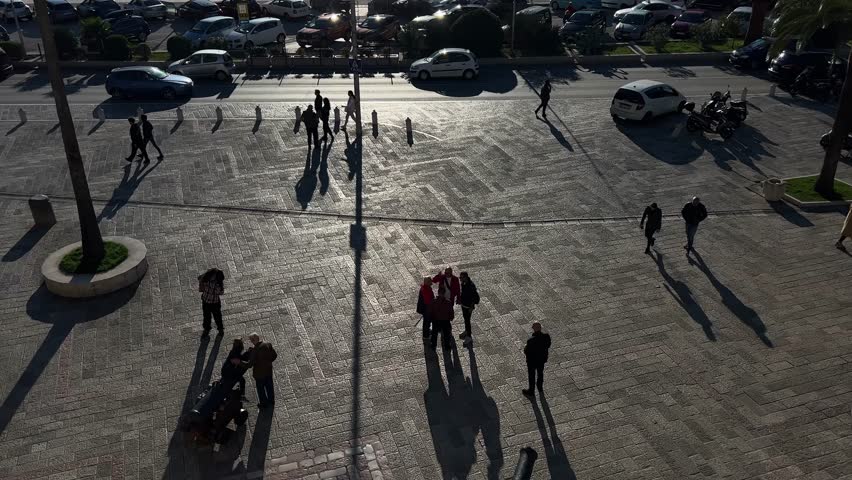 People walk along the cobbled square near the ancient cannons