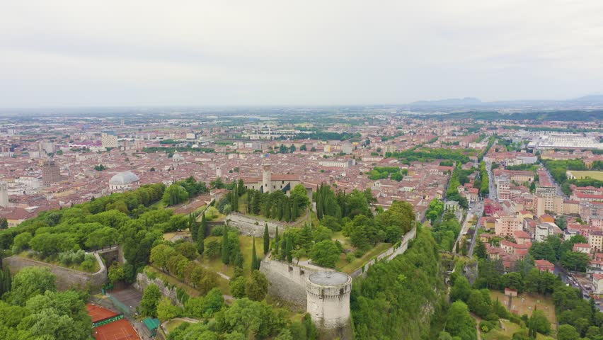 Inscription on video. Brescia, Italy. Castello di Brescia. Flight over the city in cloudy weather. Glitch effect text, Aerial View, Point of interest