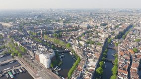 Inscription on video. Amsterdam, Netherlands. Flying over the city rooftops towards Amsterdam Central Station. Shimmers in colors purple, Aerial View