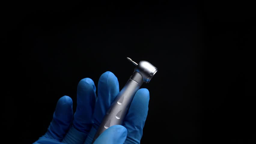 Dentist hand with drill illustrates operation of dentist dental drill machine with water. Dentist's hands with blue gloves working with dental drill in dental office. Close up, selective focus Royalty-Free Stock Footage #1102298419