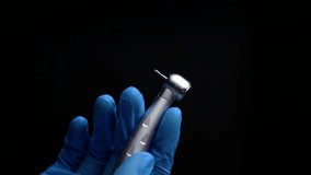 Dentist hand with drill illustrates operation of dentist dental drill machine with water. Dentist's hands with blue gloves working with dental drill in dental office. Close up, selective focus