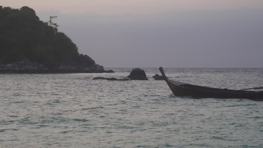 sunrise and wooden boat floating on sea near island
