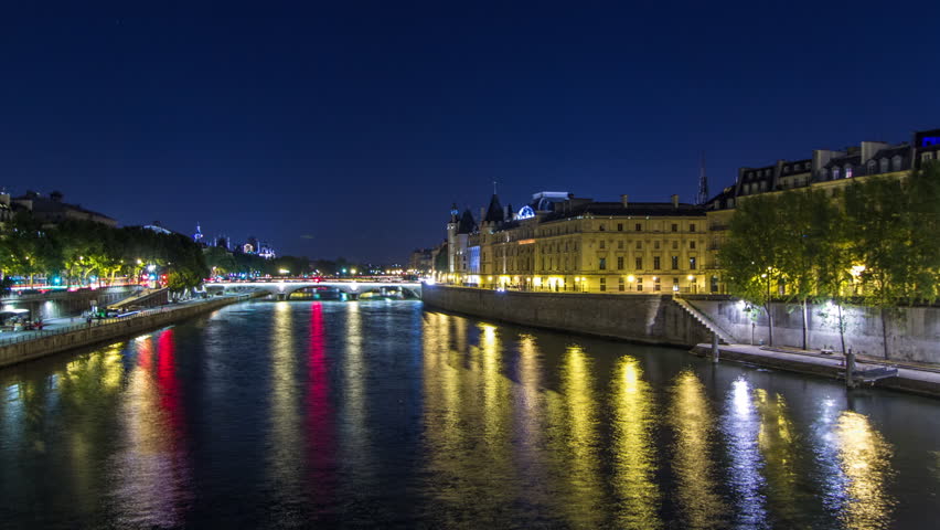 Cite island aerial view with Conciergerie Castle and Pont au Change, over the Seine river timelapse hyperlapse. Night illumination reflecter in water. France, Paris