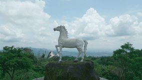 Aerial video of the landmark Horse Statue in the Kuningan Botanical Garden, Located in Kuningan, West Java. You can see the hills, shady trees surrounding the parks and thematic zones