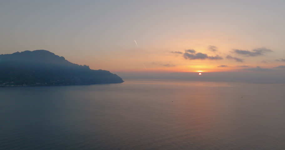 Aerial Panning Shot Of Sun Setting In Clouds By Tranquil Sea - Amalfi, Italy
