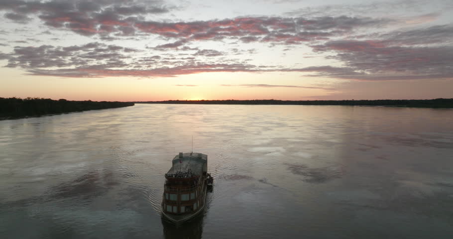 Aerial Backward Shot Of Ship Moving On Rippled Amazon River Under Cloudy During Sunset - Peruvian Amazonia, Peru Royalty-Free Stock Footage #1102307457
